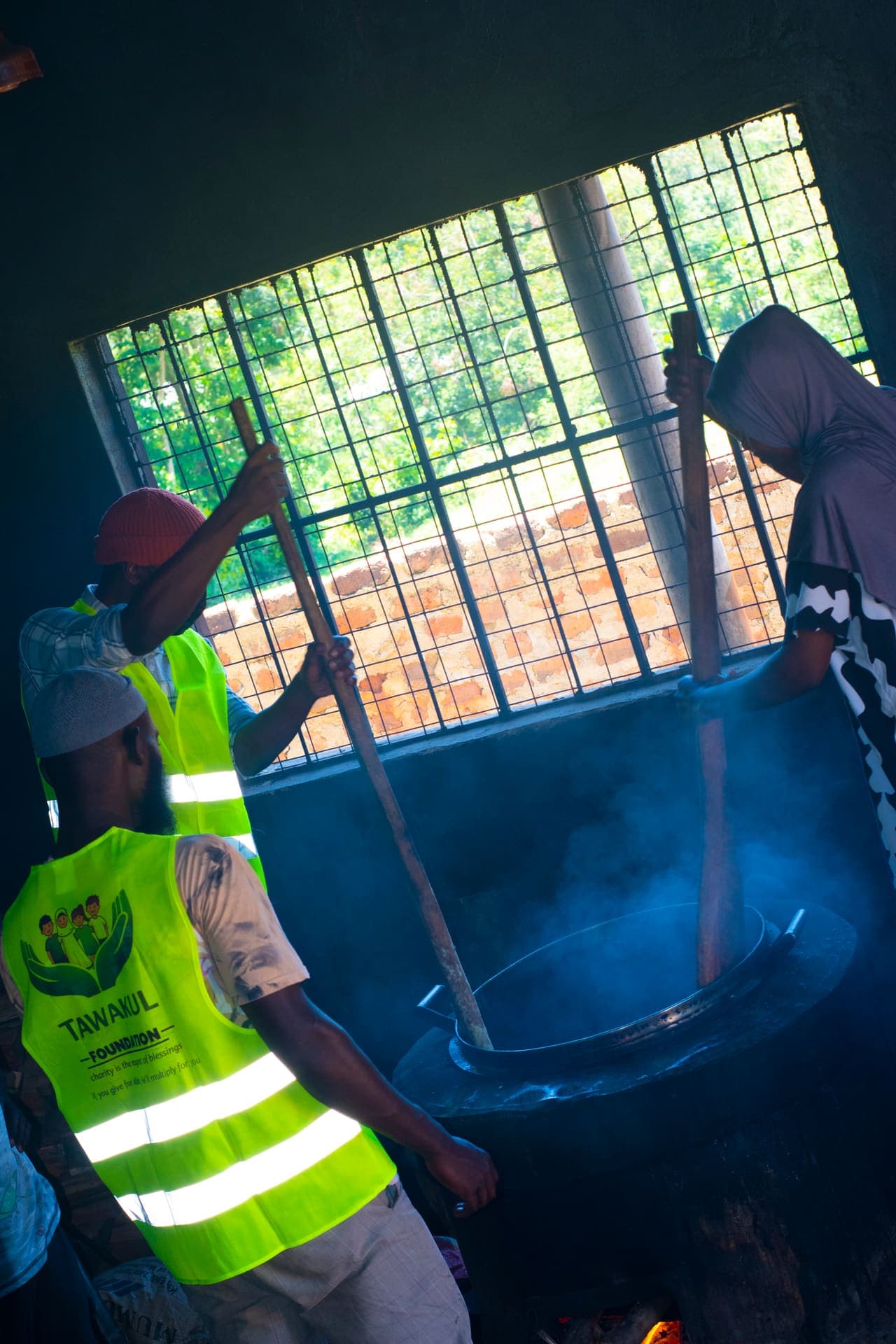 Volunteers stirring a large pot of food for the orphanage visit